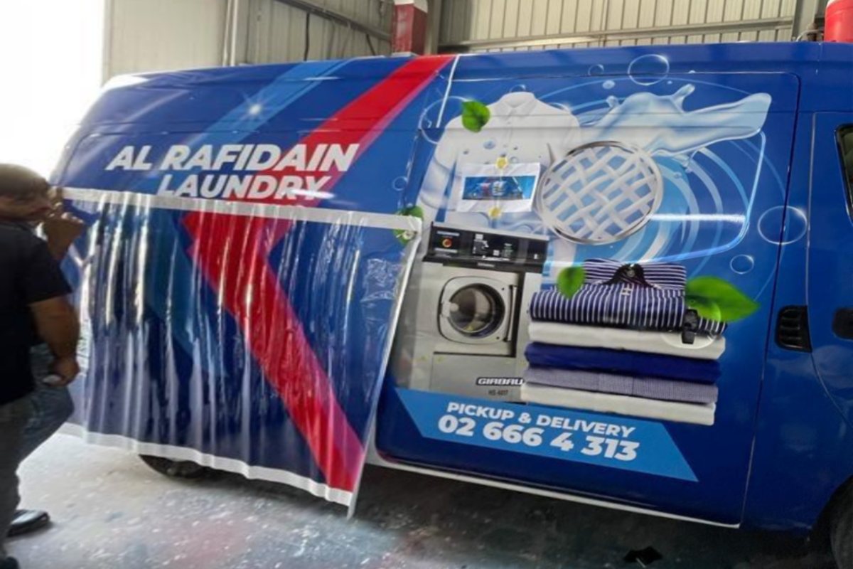 Installers applying a full wrap to an Al Rafidain Laundry van in Abu Dhabi