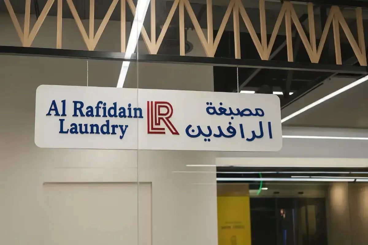 Al Rafidain Laundry White Suspended directional Sign with 3D blue lettering in Abu Dhabi by Ninety Nine Advertising LLC.
