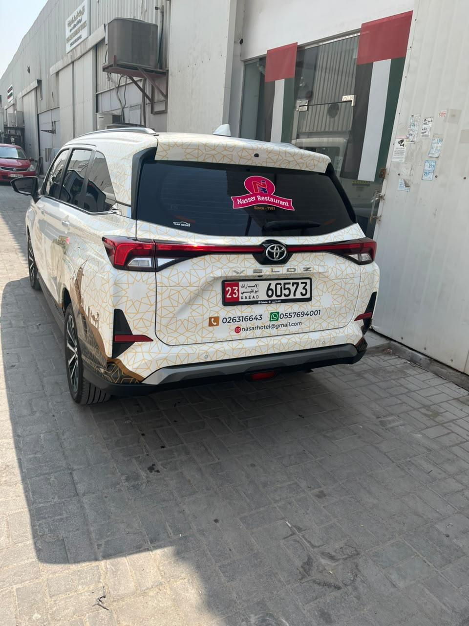 Rear branding with Nasser Restaurant logo, patterned graphics and contact details on a Toyota vehicle