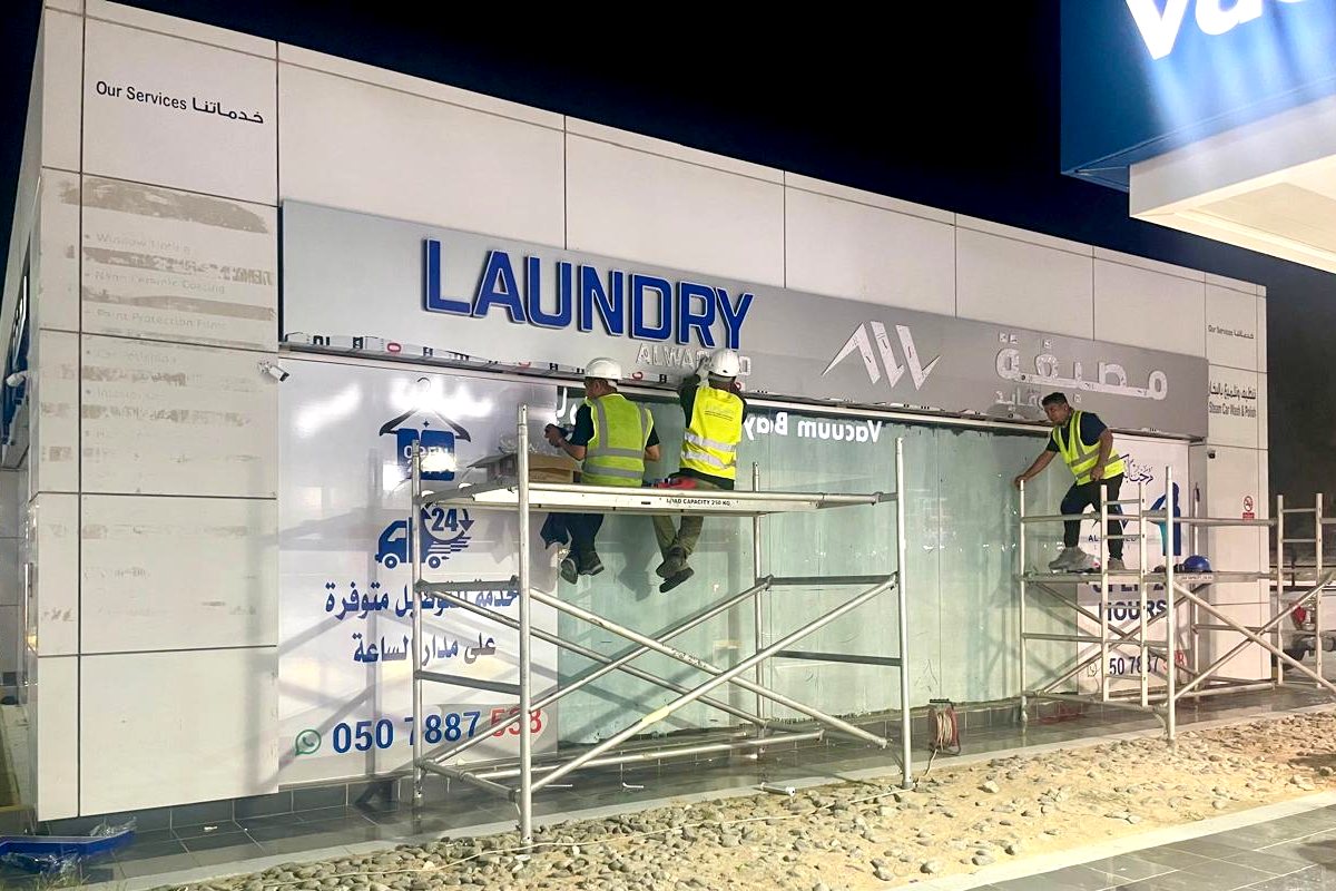 Installing a 3D storefront signboard for Al Waqaed Laundry at an ADNOC petrol station, Abu Dhabi